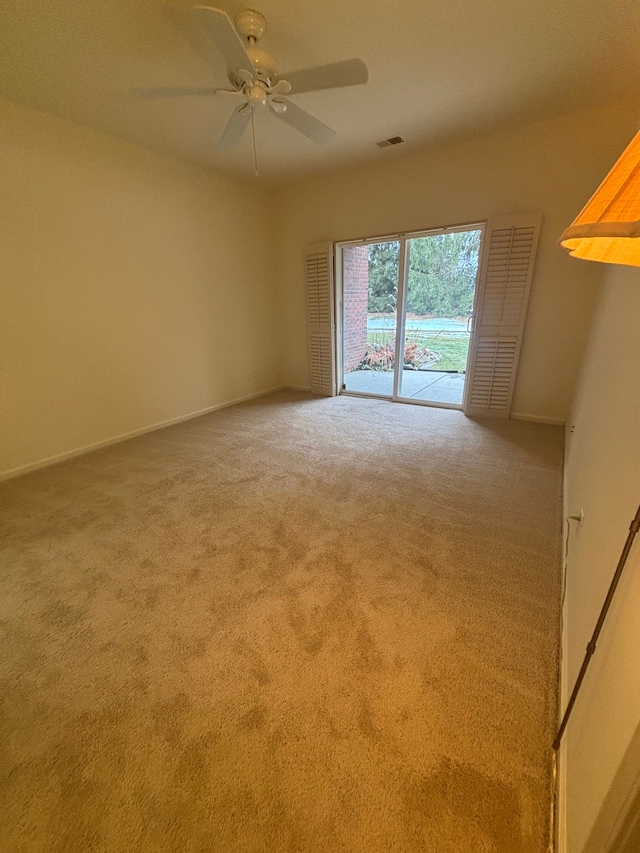 empty room with carpet floors, baseboards, visible vents, and ceiling fan