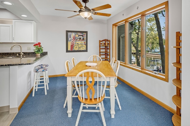 dining space featuring ceiling fan, light colored carpet, and sink