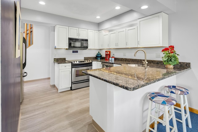 kitchen featuring kitchen peninsula, appliances with stainless steel finishes, light wood-type flooring, sink, and white cabinetry