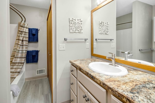 bathroom with shower / tub combo, vanity, a textured ceiling, and hardwood / wood-style flooring