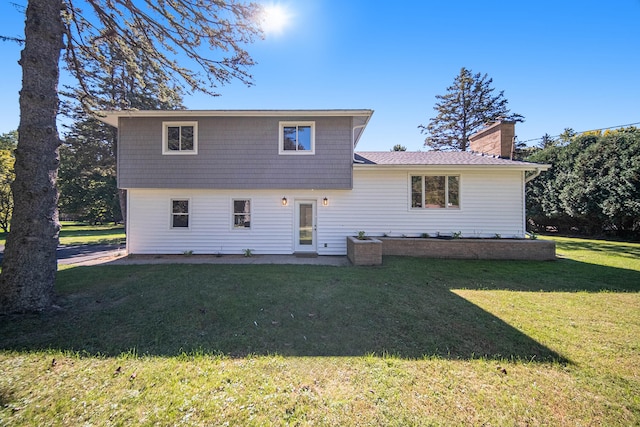 rear view of property featuring a patio area, a lawn, and a chimney