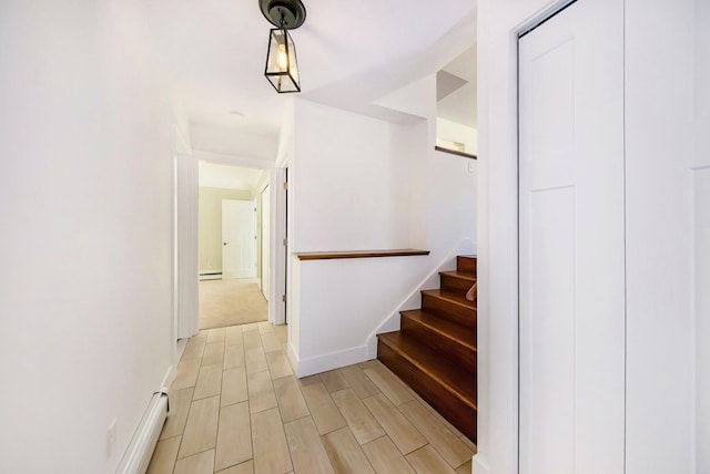 stairway with a baseboard radiator, baseboards, and wood finish floors