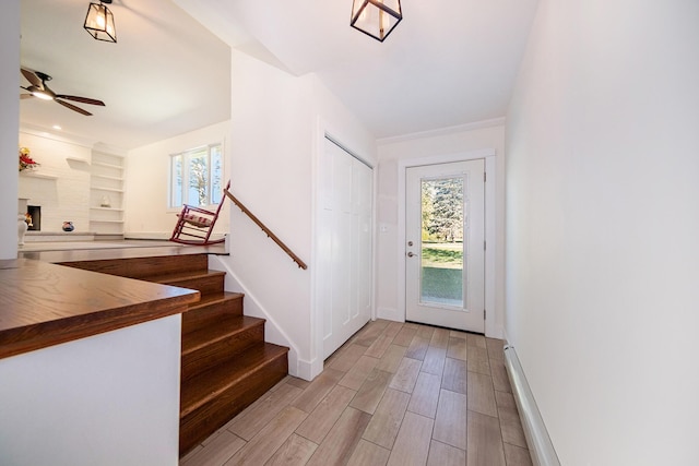 entryway featuring plenty of natural light, a large fireplace, baseboards, and wood finished floors