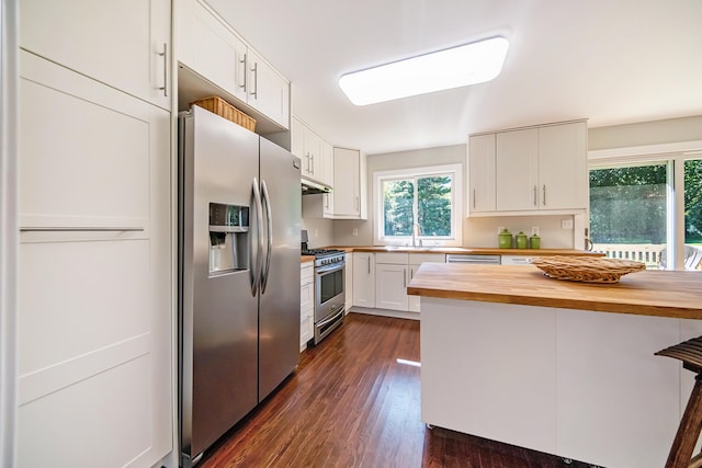 kitchen with wooden counters, dark wood-style flooring, appliances with stainless steel finishes, white cabinets, and a sink