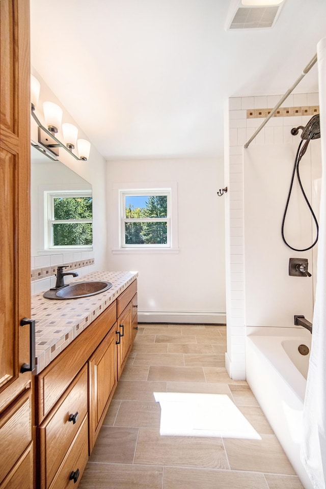 bathroom featuring visible vents, baseboards, baseboard heating, bathing tub / shower combination, and vanity