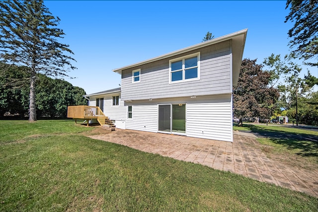 back of property featuring a lawn, a wooden deck, and a patio