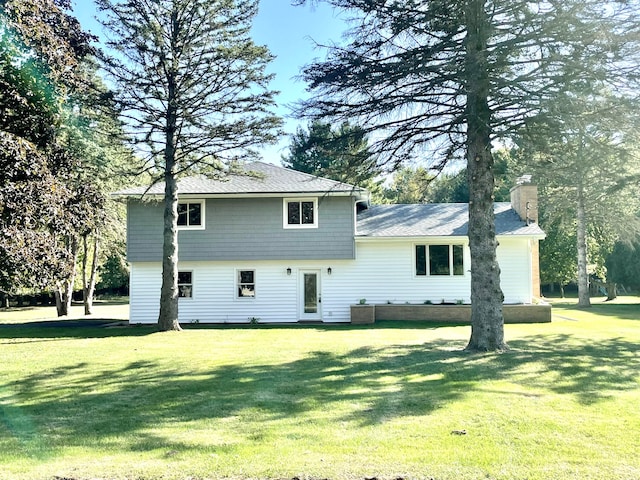 back of house with a yard and a chimney