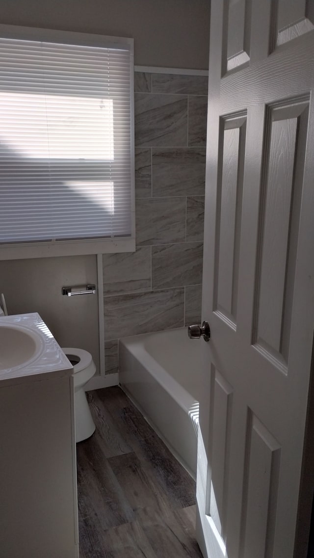 bathroom featuring hardwood / wood-style floors, vanity, toilet, and tile walls