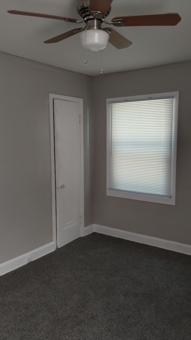 spare room featuring dark colored carpet and ceiling fan