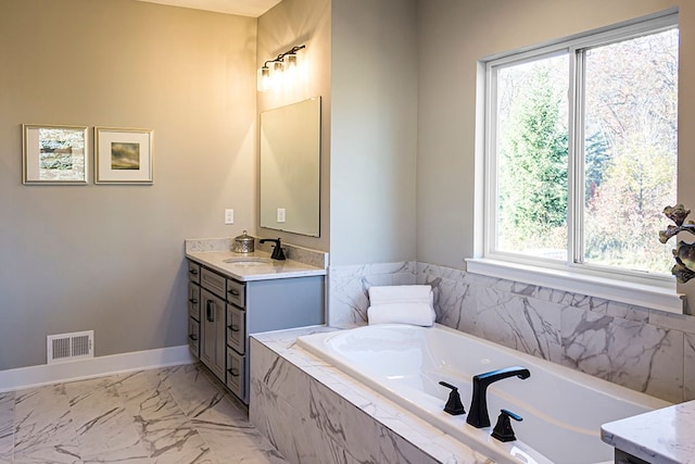 bathroom with vanity, tiled tub, and a wealth of natural light