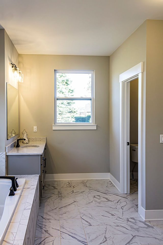 bathroom featuring vanity, tiled bath, and toilet