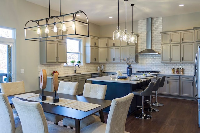 kitchen featuring backsplash, wall chimney exhaust hood, dark hardwood / wood-style floors, decorative light fixtures, and a kitchen island