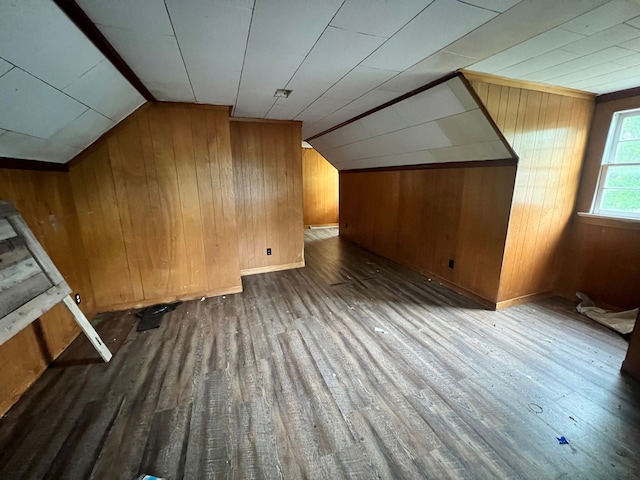 additional living space with dark hardwood / wood-style flooring, vaulted ceiling, and wood walls