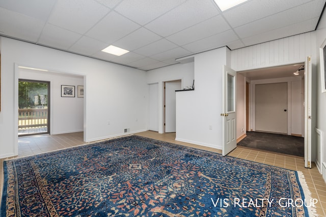 spare room with tile patterned floors and a paneled ceiling