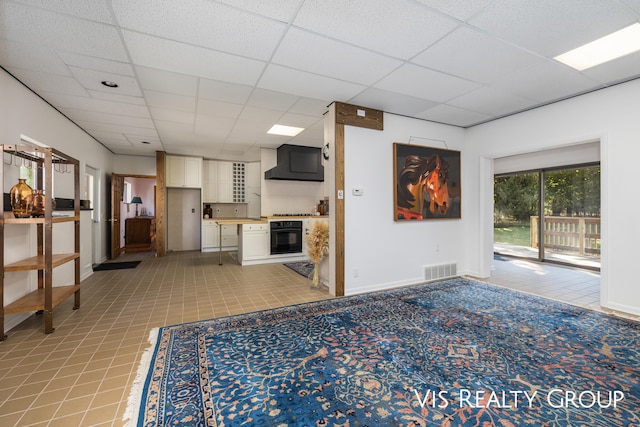 unfurnished living room featuring a paneled ceiling and light tile patterned floors