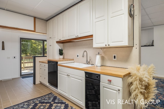 kitchen with a paneled ceiling, light tile patterned flooring, white cabinets, and sink