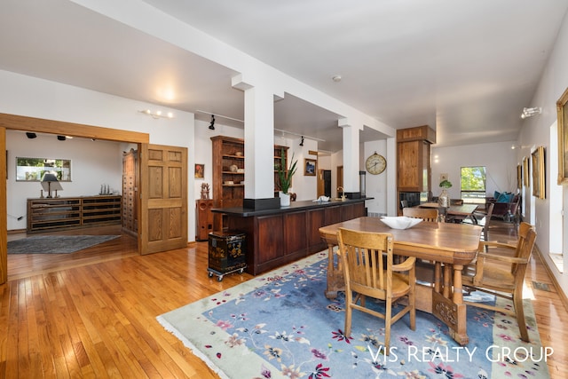 dining area featuring ornate columns and light hardwood / wood-style flooring