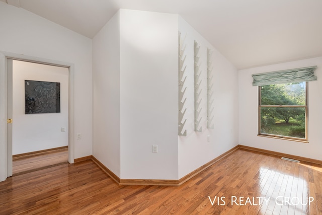 unfurnished room with hardwood / wood-style flooring and lofted ceiling