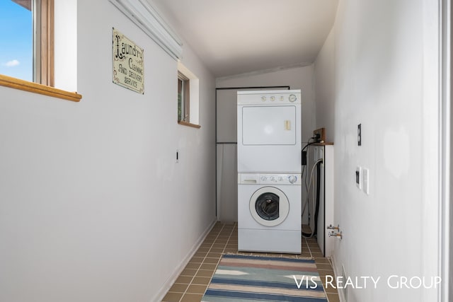 clothes washing area featuring dark tile patterned flooring and stacked washer and dryer