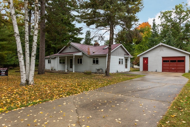 1758 W Nestel Rd, Prudenville, MI 48651 - ranch-style home with a garage, an outbuilding, concrete driveway, metal roof, and covered porch