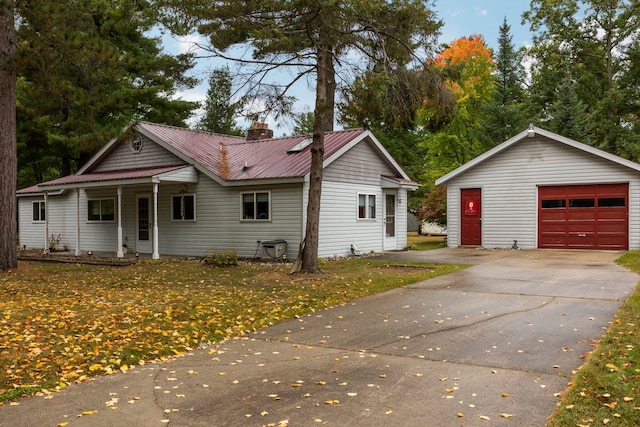 1758 W Nestel Rd, Prudenville, MI 48651 - view of front of home featuring a detached garage, a chimney, an outbuilding, a porch, and metal roof