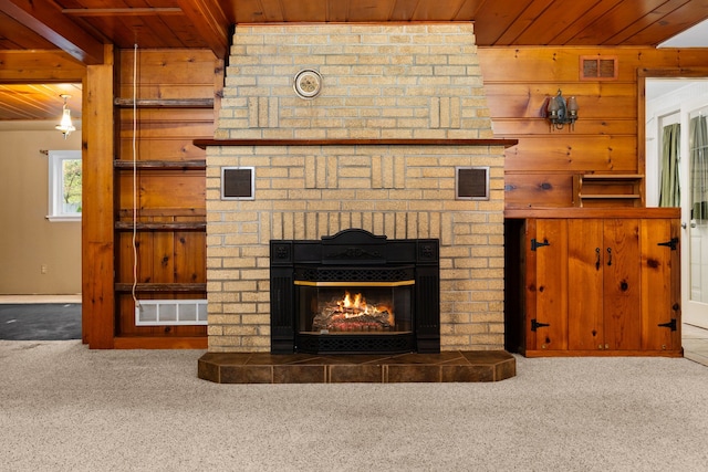 interior details with wooden walls, carpet, wooden ceiling, and a brick fireplace