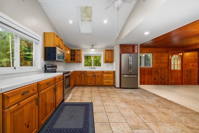 1758 W Nestel Rd, Prudenville, MI 48651 - kitchen featuring appliances with stainless steel finishes, a sink, lofted ceiling, brown cabinetry, and tasteful backsplash