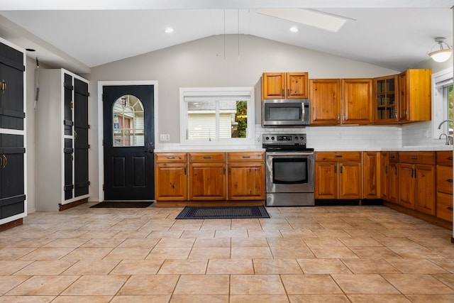 kitchen with decorative backsplash, stainless steel appliances, vaulted ceiling, and light tile patterned flooring