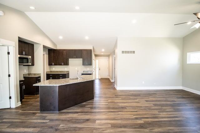 kitchen with sink, dark wood-type flooring, a kitchen island with sink, and vaulted ceiling