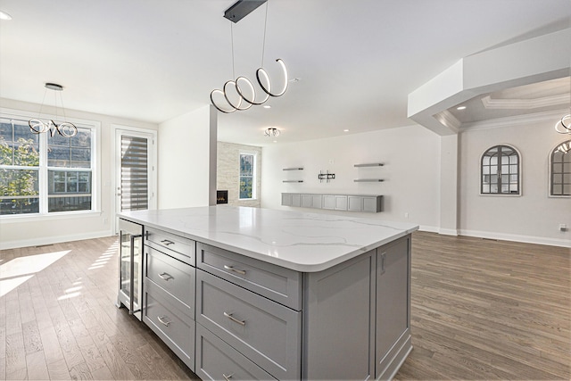 kitchen with light stone counters, gray cabinetry, pendant lighting, dark hardwood / wood-style floors, and wine cooler