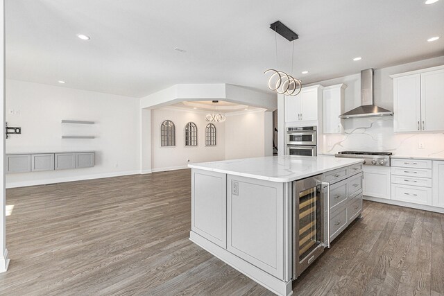 kitchen featuring wall chimney exhaust hood, wood-type flooring, white cabinets, a center island, and wine cooler