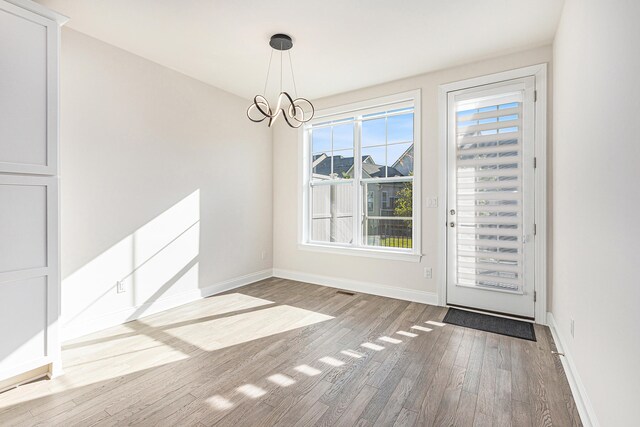 unfurnished dining area featuring hardwood / wood-style floors and a chandelier