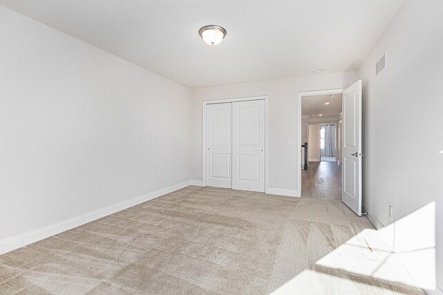 unfurnished bedroom with light carpet and a closet