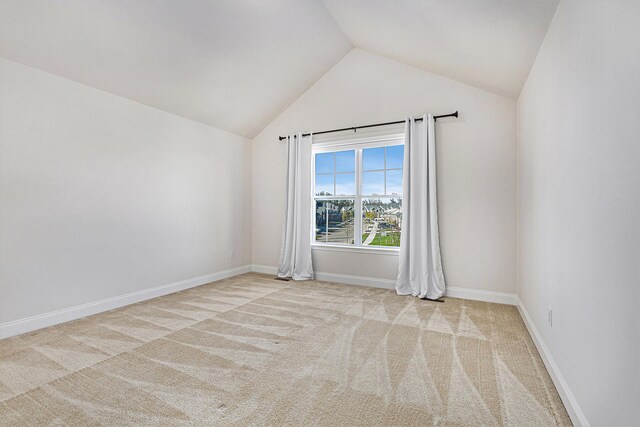 spare room with light colored carpet and vaulted ceiling