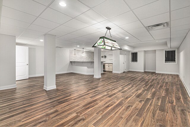 unfurnished living room with a paneled ceiling and dark hardwood / wood-style floors