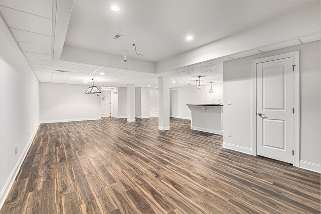 unfurnished living room featuring a drop ceiling and dark wood-type flooring