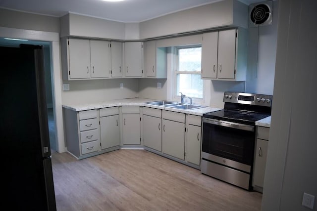 kitchen with black refrigerator, sink, gray cabinets, light hardwood / wood-style floors, and stainless steel range with electric cooktop