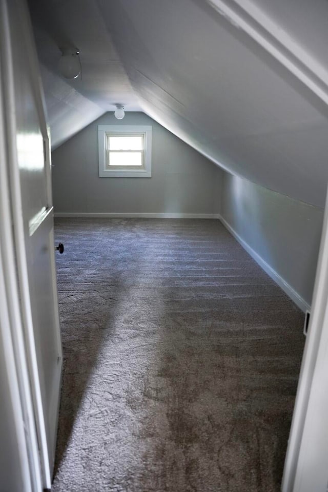 additional living space featuring dark colored carpet and vaulted ceiling