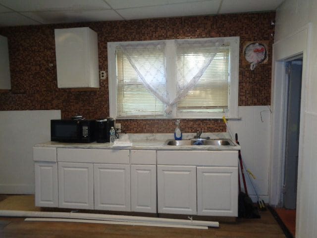 kitchen with a paneled ceiling, white cabinetry, sink, and dark hardwood / wood-style flooring