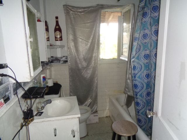 full bathroom with tile patterned flooring, vanity, toilet, and tile walls