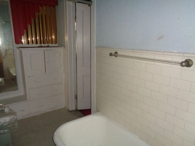 bathroom with tile patterned flooring, a bathtub, and tile walls