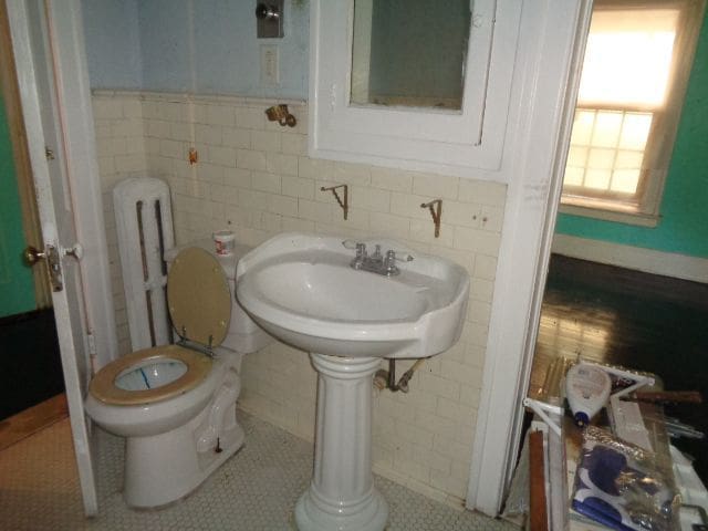 bathroom featuring tile patterned flooring, toilet, tile walls, and sink