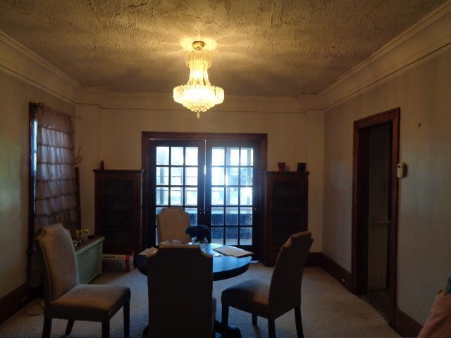 dining space featuring carpet flooring, french doors, a textured ceiling, crown molding, and a notable chandelier