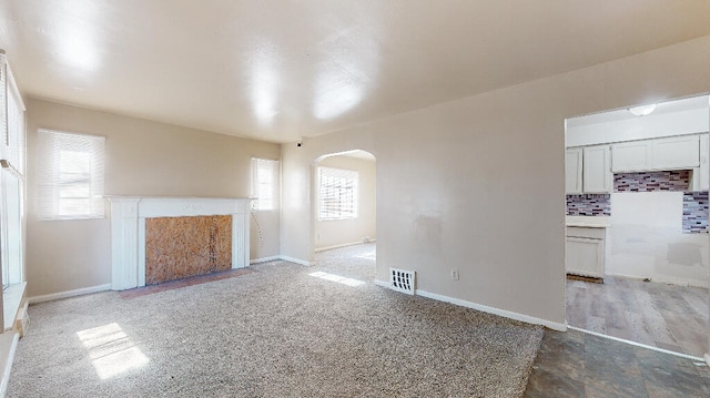 unfurnished living room with carpet flooring and plenty of natural light