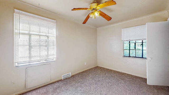 carpeted spare room featuring ceiling fan and a healthy amount of sunlight