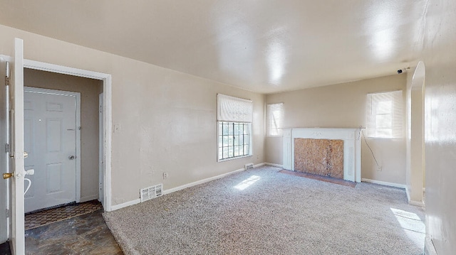 unfurnished living room featuring dark carpet and a wealth of natural light