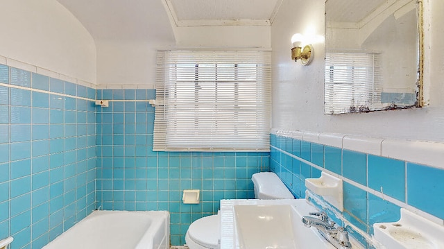 bathroom with a tub to relax in, tile walls, and a healthy amount of sunlight