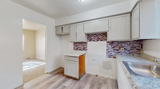 kitchen with decorative backsplash, light hardwood / wood-style floors, and sink