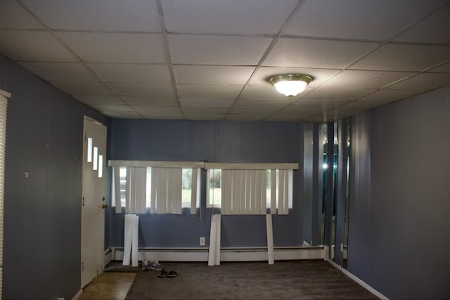 carpeted spare room with a paneled ceiling and a baseboard radiator