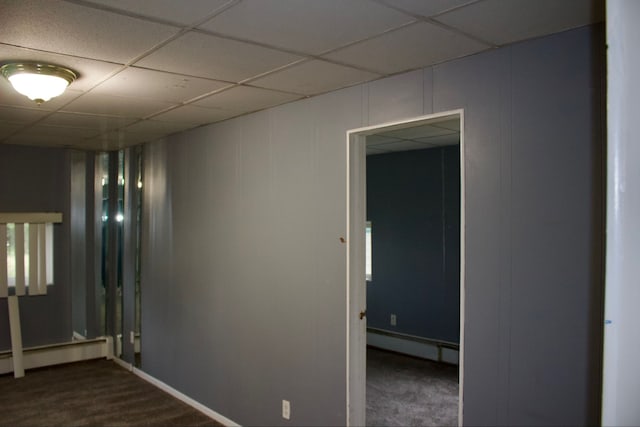 carpeted empty room with baseboard heating and a drop ceiling